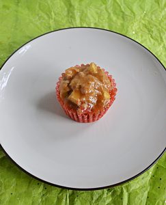 A plate with a single brown sugar glazed apple cupcake on it.