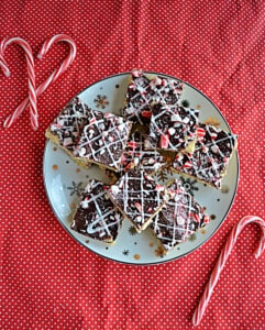 A plate of peppermint bark cookies with candy canes around the plate.