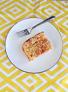 A plate with a slice of baked pineapple with a fork on the plate.