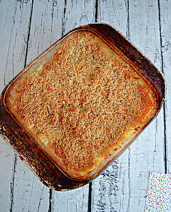 A baking dish of hash brown casserole topped with golden brown breadcrumbs.