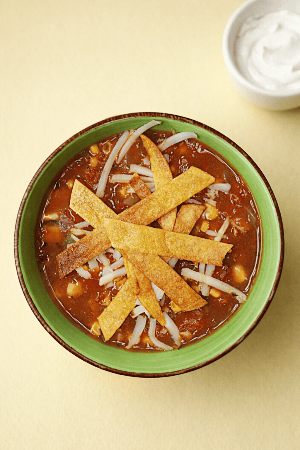 A top view of a bowl of soup with crispy tortillas on top.