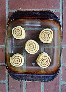 A baking dish with 5 unbaked cinnamon rolls in it.