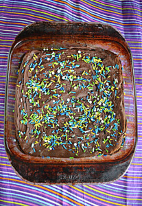 A pan of brownies covered in chocolate ganache and blue and green sprinkles.