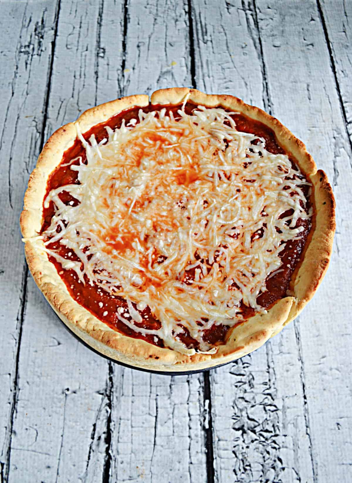A deep dish pizza with golden crust, plenty of sauce, and a sprinkle of cheese on top.