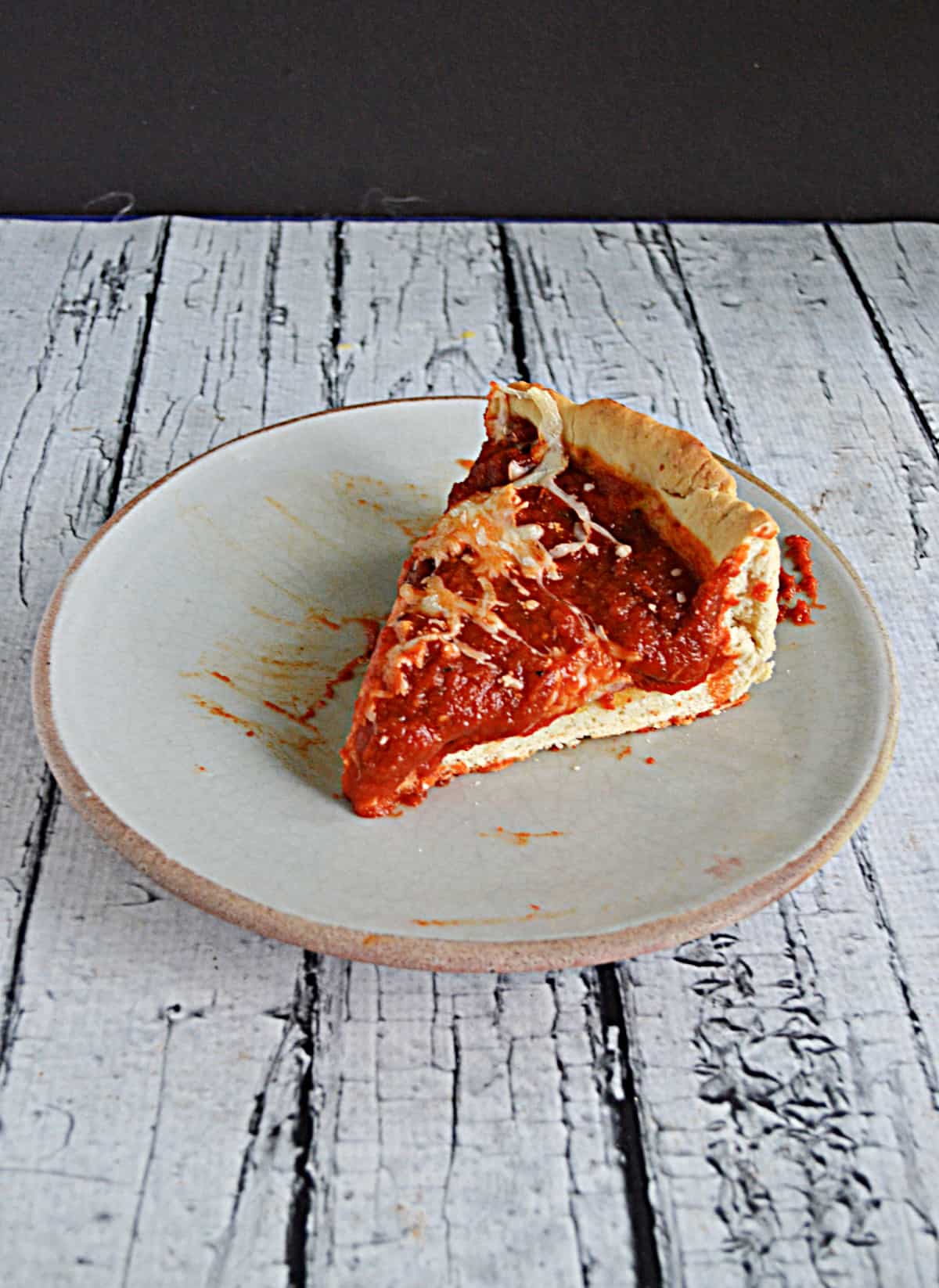 A plate with a slice of deep dish pizza on it.