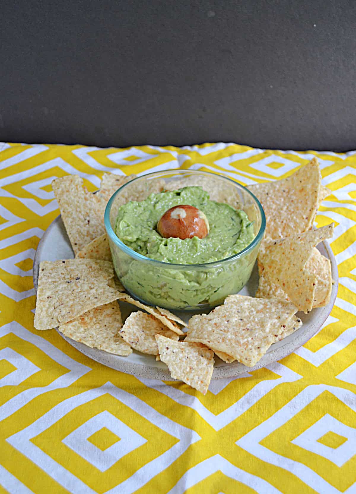 A plate of tortilla chips and guacamole.