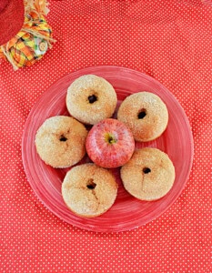 A plate of donuts with an apple in the middle.