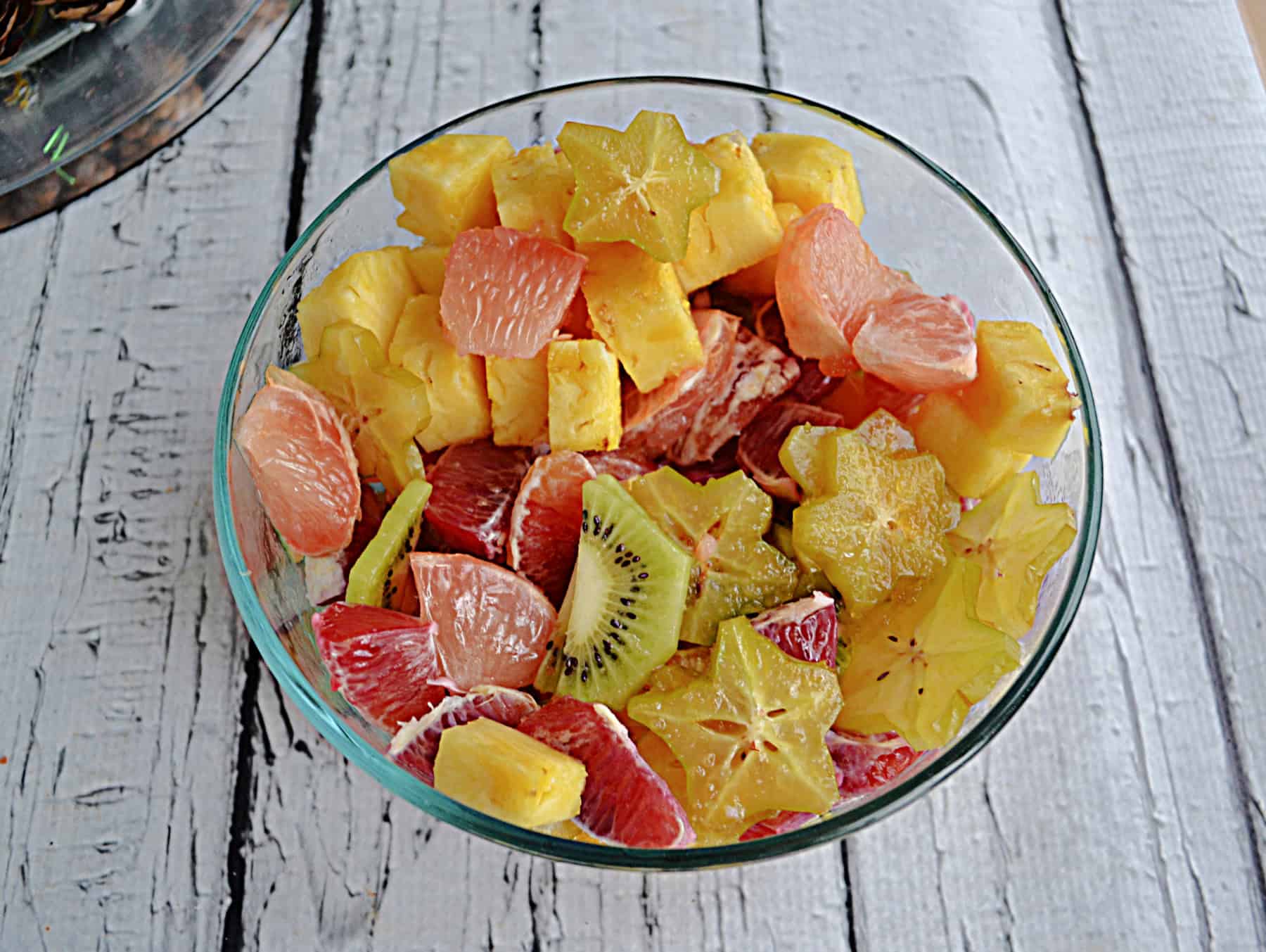 A bowl of kiwi, pineapple, star fruit, oranges, and grapefruit.