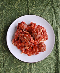 A plate of spaghetti and meatballs with marinara sauce.