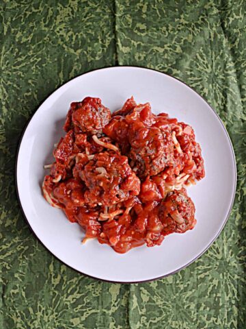 A plate of spaghetti and meatballs with marinara sauce.