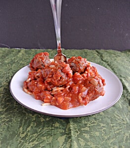 A plate of spaghetti and meatballs with a fork sticking out of it.