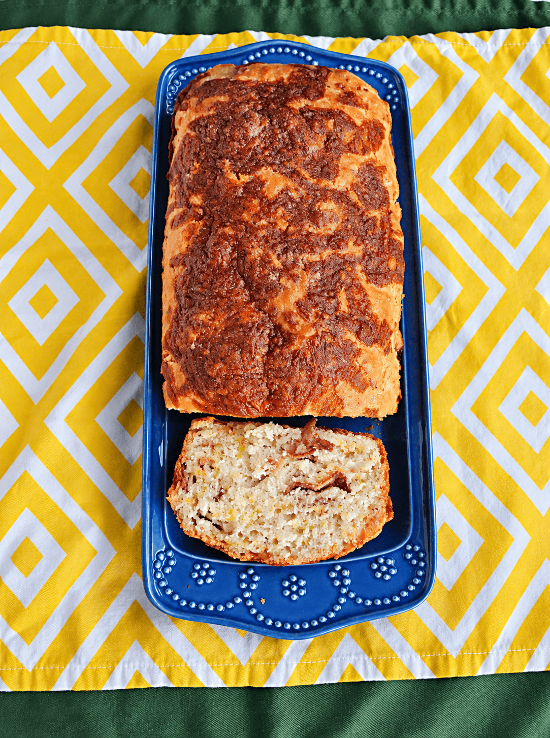 A loaf of bread on a platter with a slice cut off.