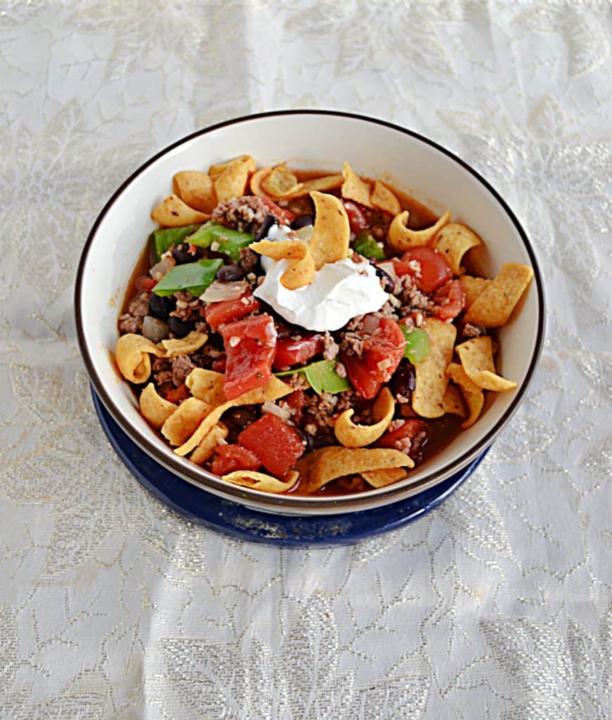 A bowl filled with corn chips and chili with a dollop of sour cream on top. 