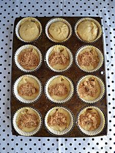 A pan of cupcakes with half of them topped with a cinnamon mixture.