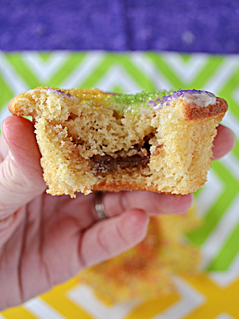 A close up view of a cupcake with a bite taken out of it and the cinnamon filling shown inside. 