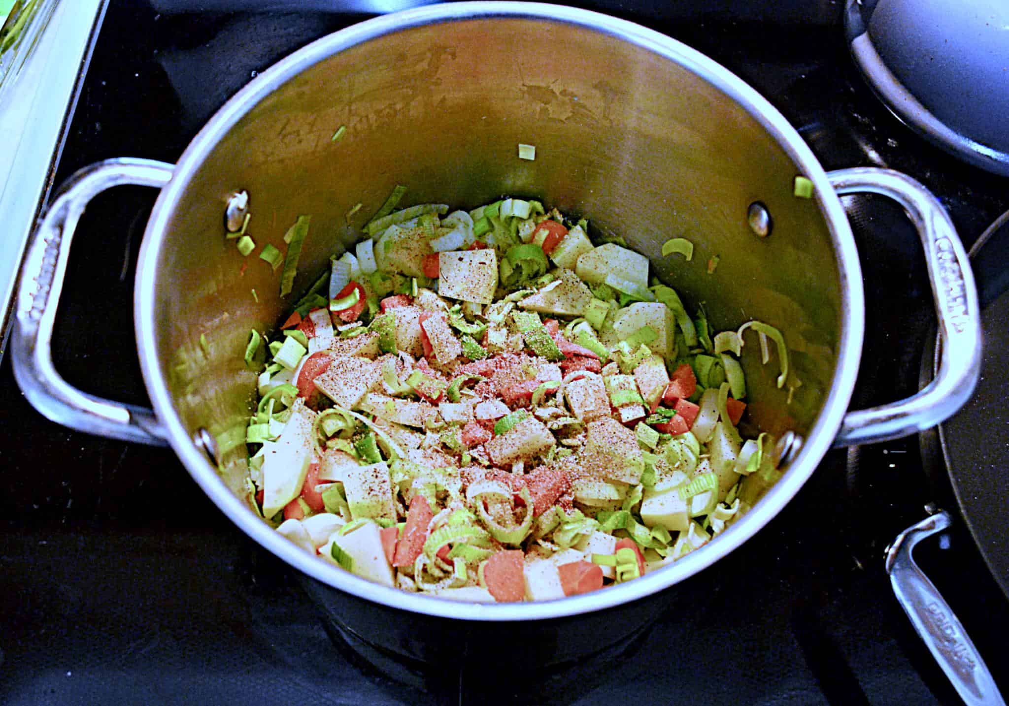 A soup pot filled with leeks , potatoes, and carrots.
