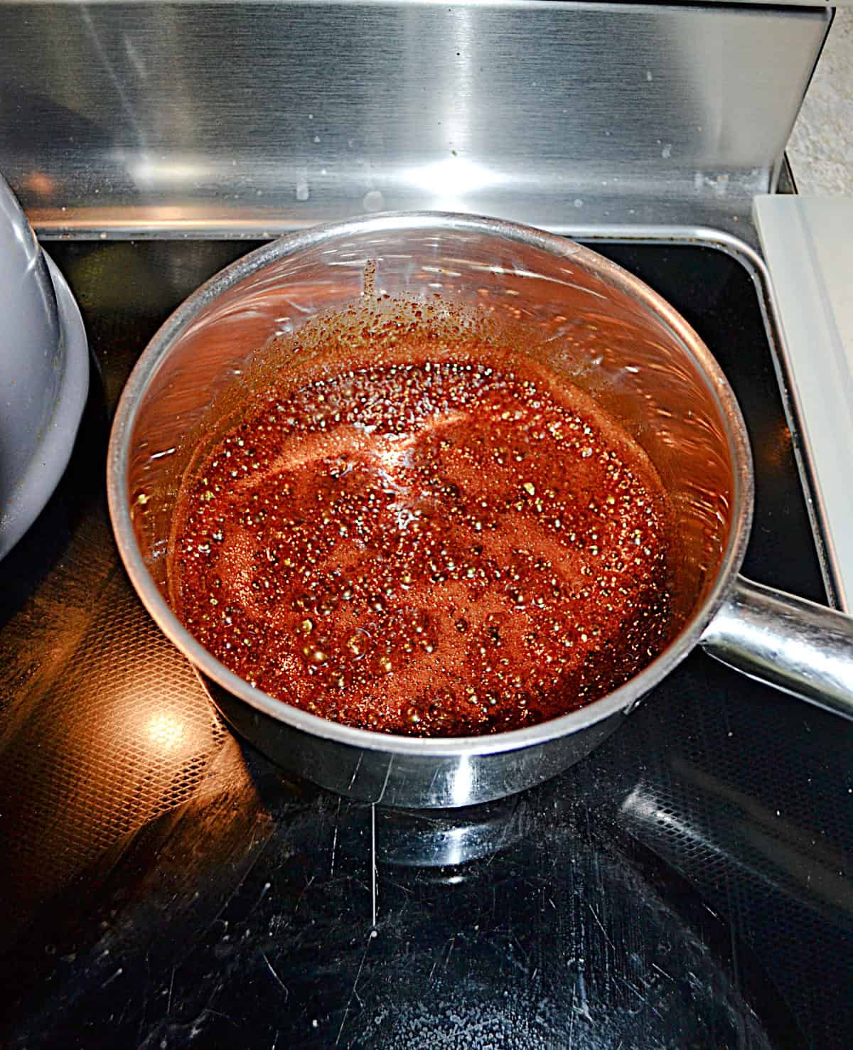 A saucepan with brown sauce in it.