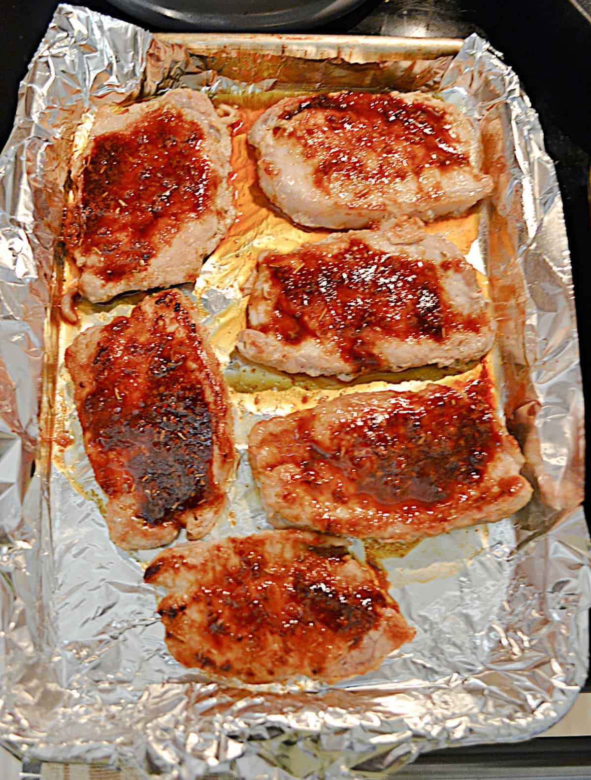 A pan with pork chops and sauce on it.