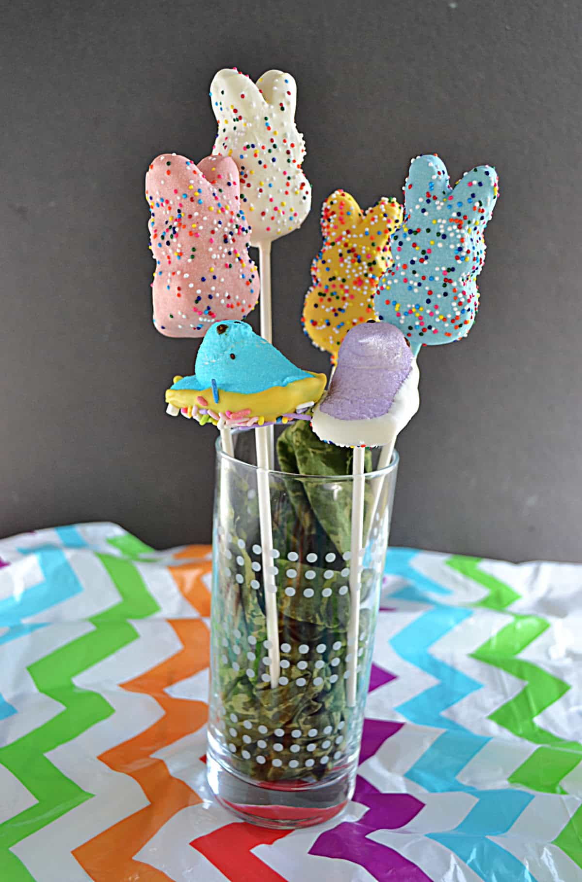 A vase with chocolate covered peeps on a stick.