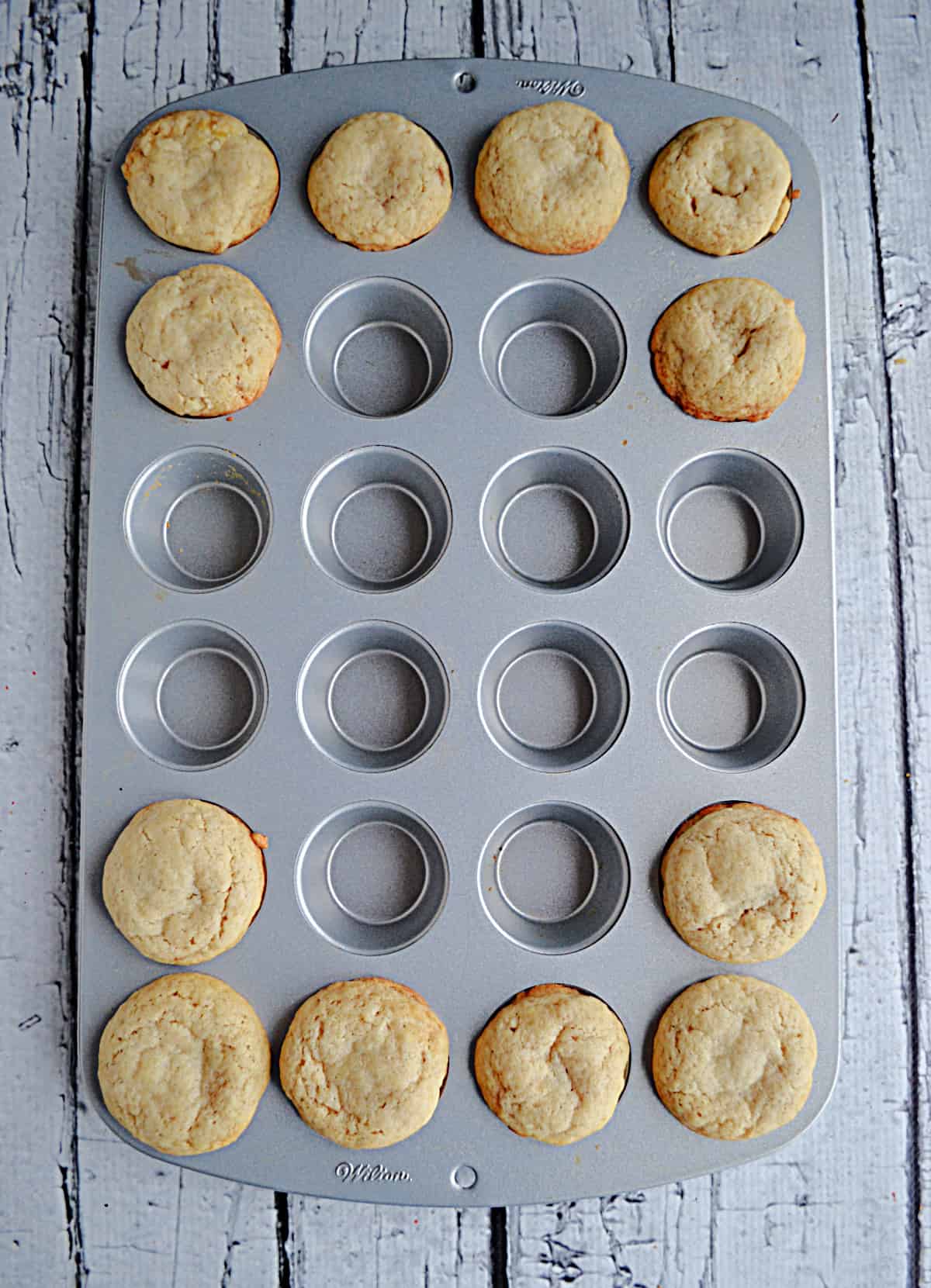A mini muffin tin with sugar cookie dough in it.