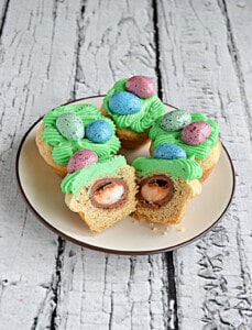 A plate of Easter egg surprise cookies with one cookie cut in half to show the Cadbury egg filling.