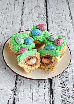 A plate of Easter egg surprise cookies with one cookie cut in half to show the Cadbury egg filling.