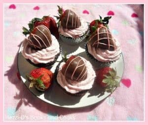 A plate with four cupcakes on it topped with chocolate covered strawberries