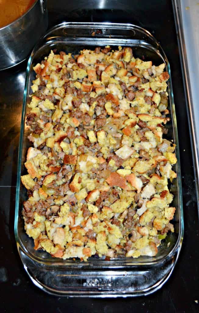 A baking dish filled with cornbread and white bread stuffing with bits of sausage, celery, and mushrooms mixed in. 