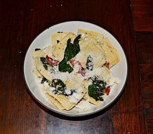 Ravioli Florentine in a bowl topped with spinach, bacon, and parmesan cheese.
