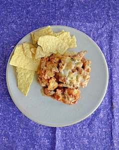 A plate with tortilla chips and a scoop of chicken tamale pie.
