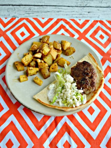 Lamb burger, feta, and lettuce in a pita with Greek potatoes all on a plate