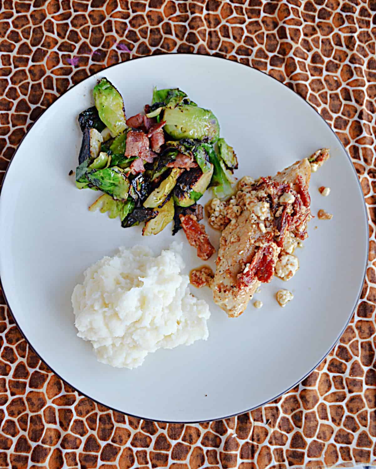 A plate with chicken, potatoes, and brussels sprouts.