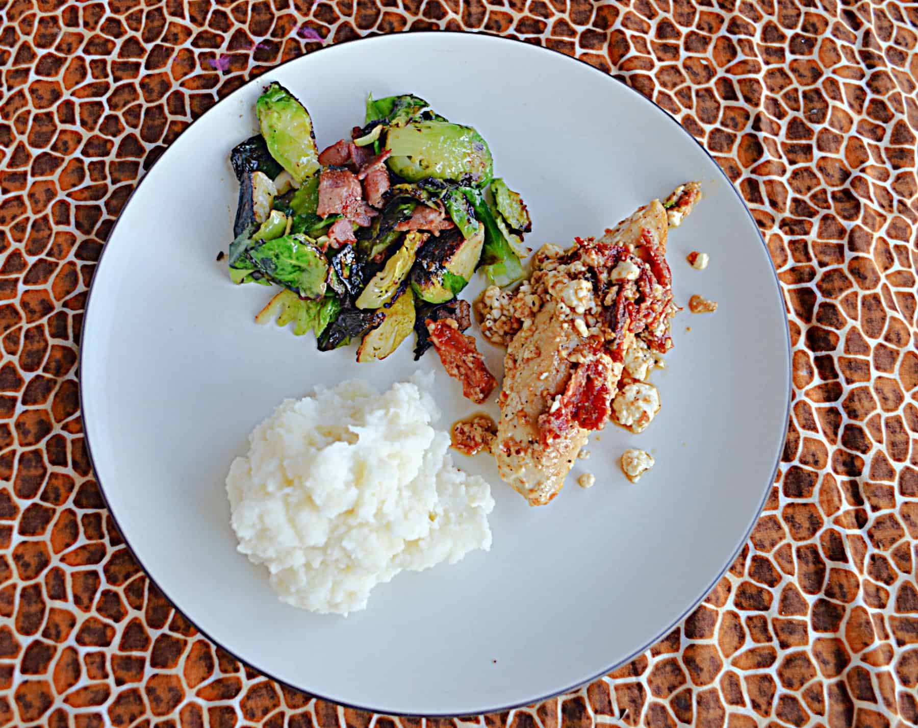 A plate with feta chicken, mashed potatoes, and Brussels Sprouts