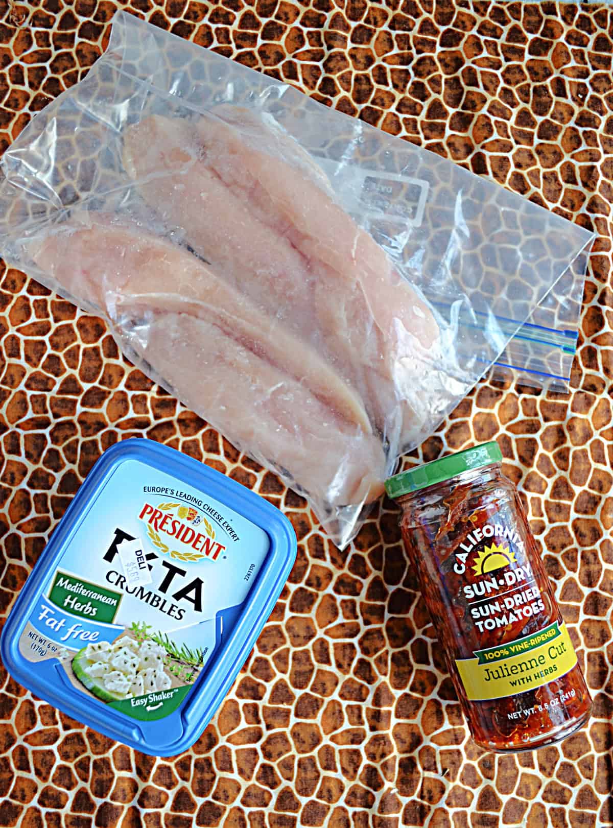 Chicken, a jar of sun dried tomatoes, and a container of fetaa cheese.