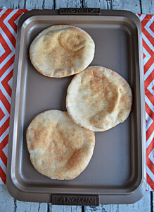 A baking sheet with three pitas on it.