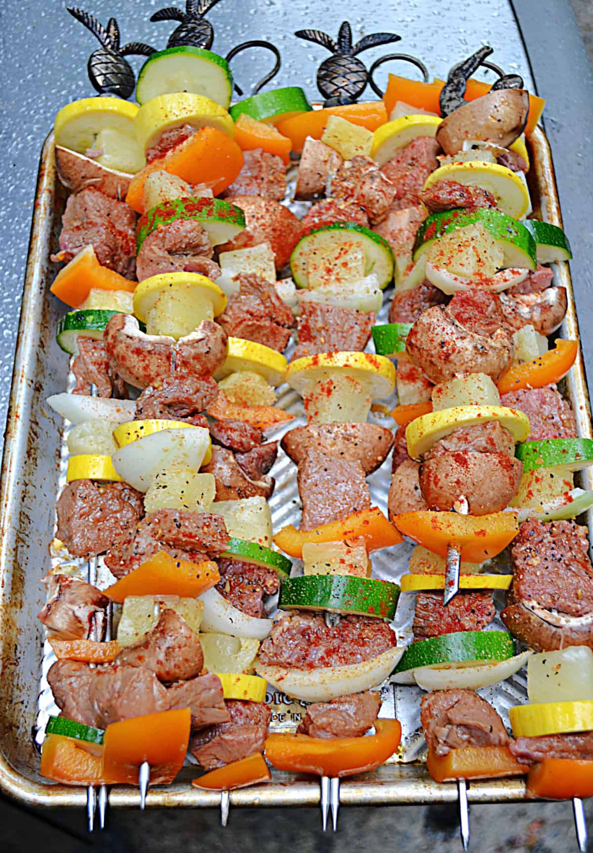 A pan full of vegetable and beef kabobs on skewers.