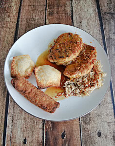 A plate with 2 pork chops, 2 wontons, and an egg roll.