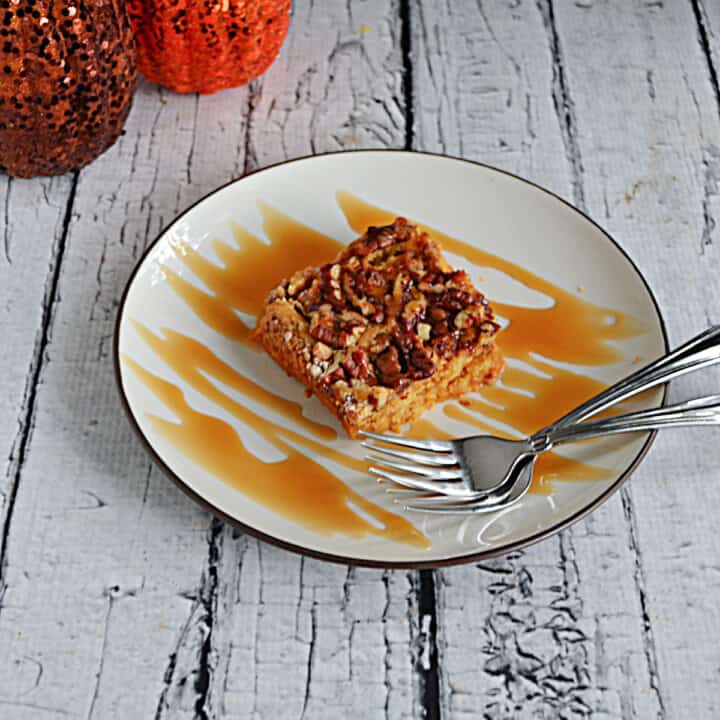 A plate with a slice of pumpkin cake with a caramel drizzle and two forks.