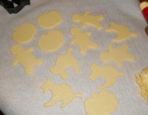 A piece of parchment wit cut out cookie dough shapes on it.