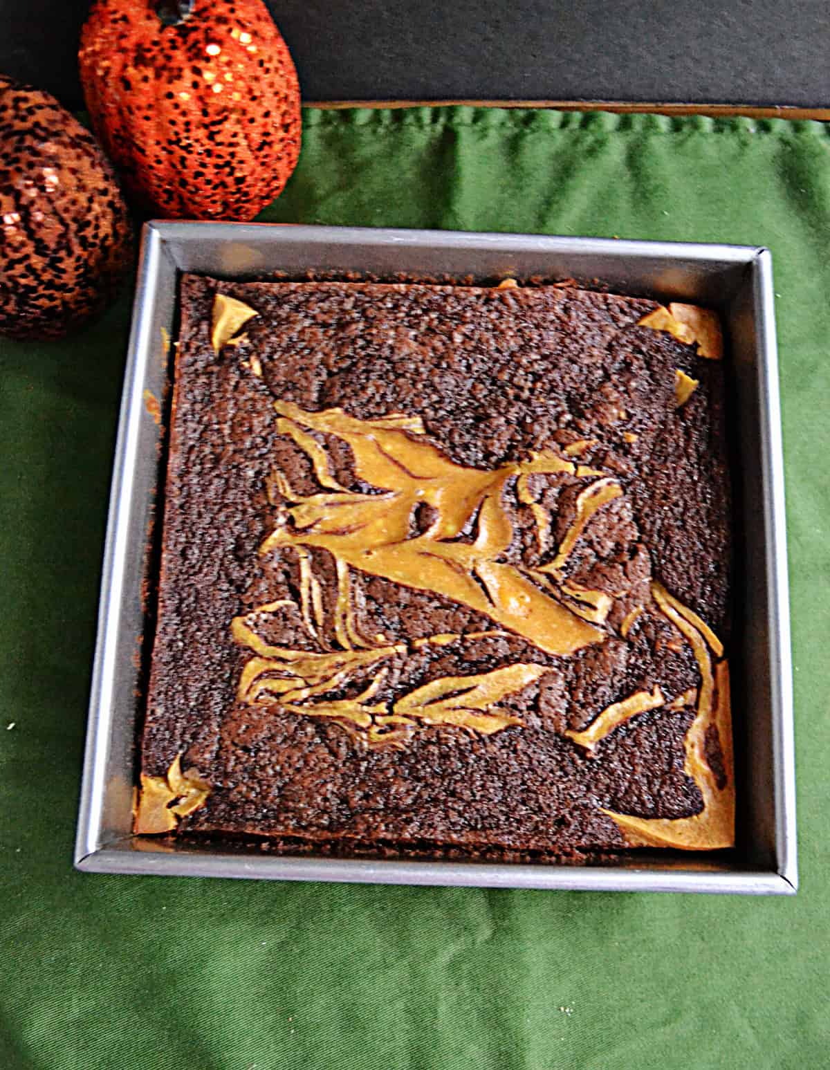 A pan of brownies with a pumpkin cheesecake swirl.