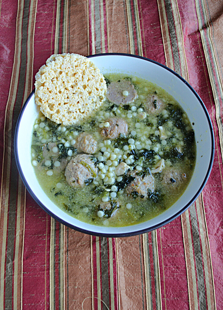 A bowl of Italian Wedding Soup with a cheese crisp on the side.