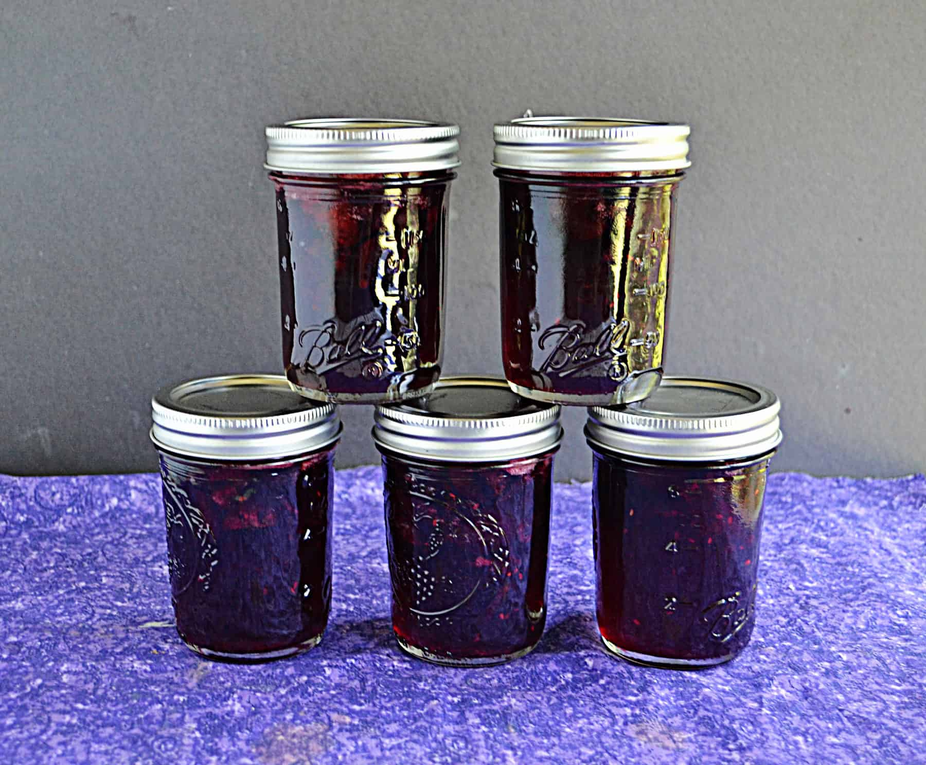 Jars of cherry jam stacked on top of each other.