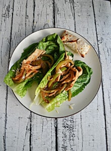 A plate with two lettuce wraps filled with chicken and peppers.
