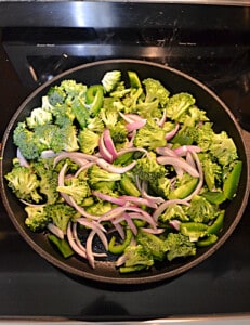 A skillet of onions and broccoli.
