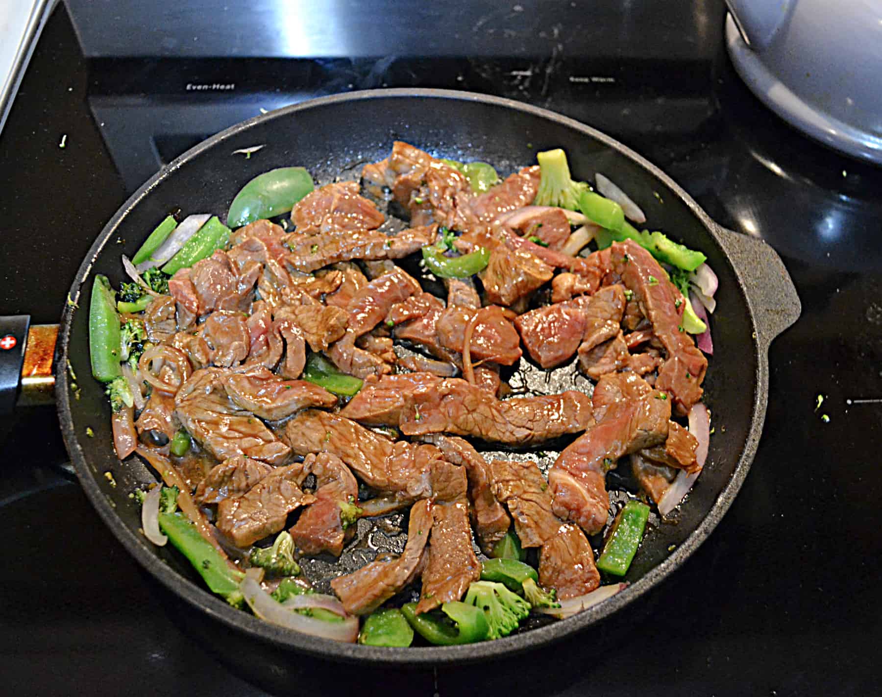 A skillet with beef and broccoli in it.