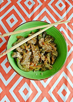 A bowl of beef and broccoli with chopsticks on top.