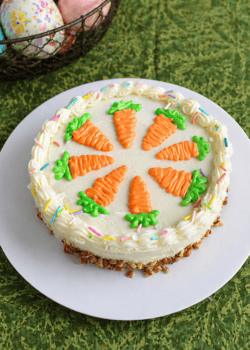 A cake with white frosting decorated with frosting carrots on top.