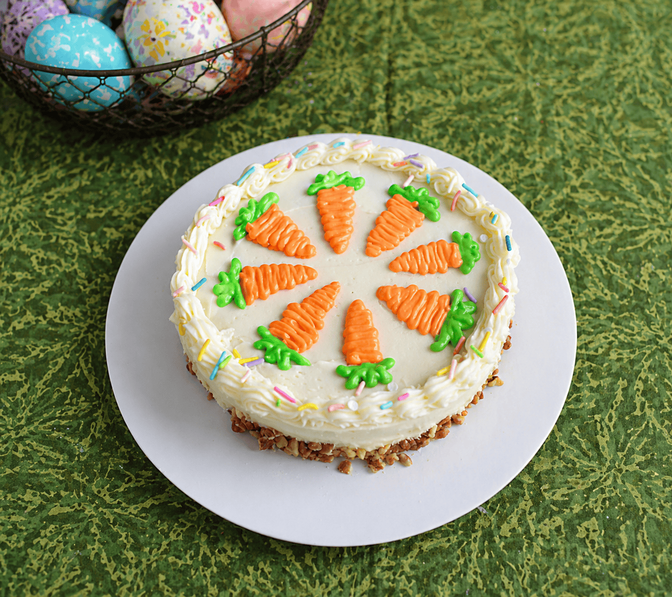 A cake with white frosting decorated with frosting carrots on top. 