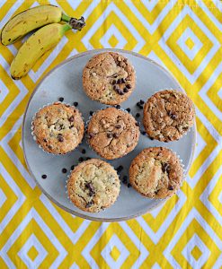 A plate filled with banana chocolate chip muffins and two bananas on the side.