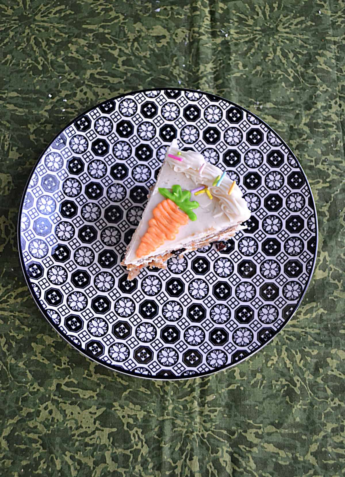 A top view of a slice of carrot cake with a frosting carrot on top.